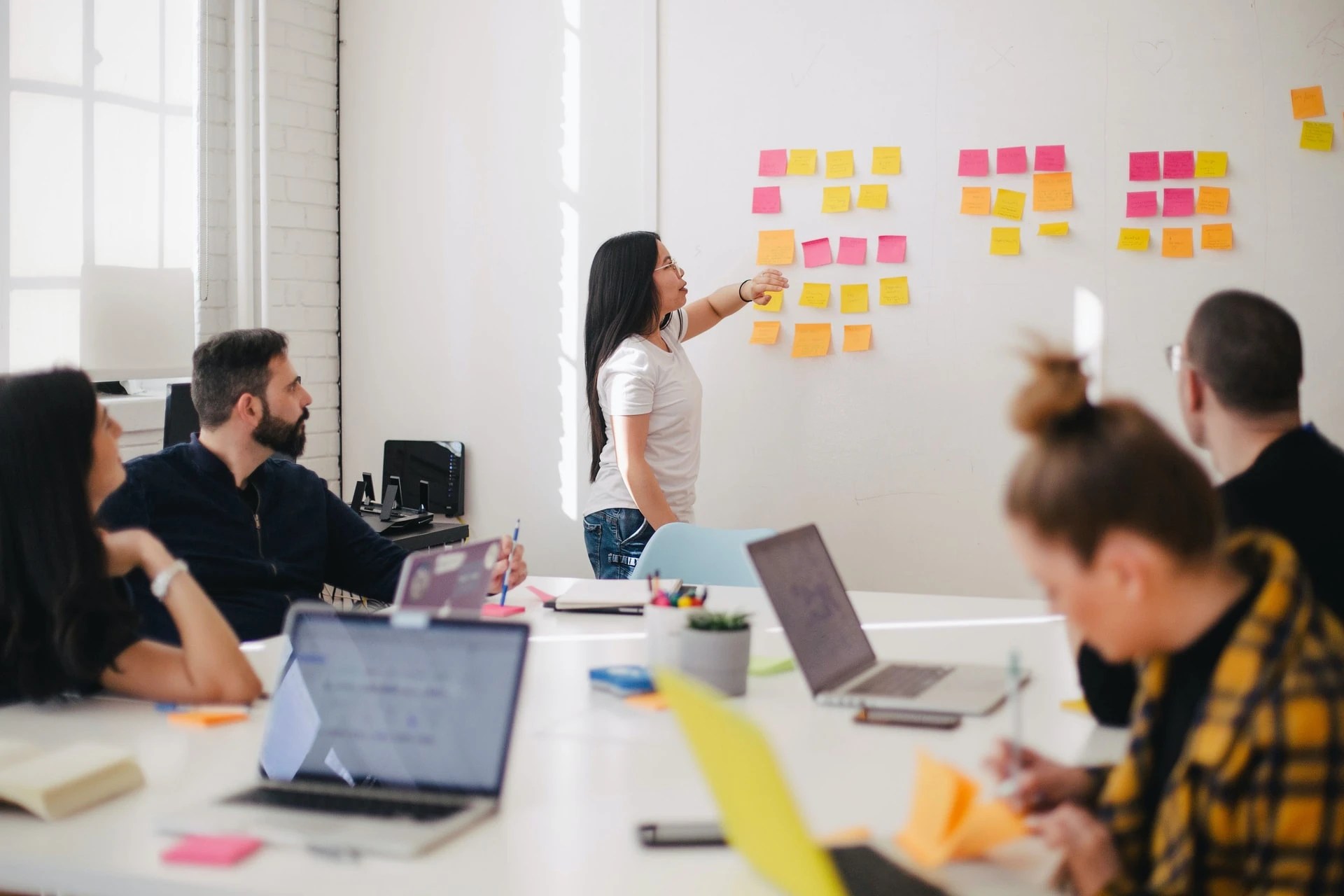 Team member presenting ideas on sticky notes during a collaborative office meeting